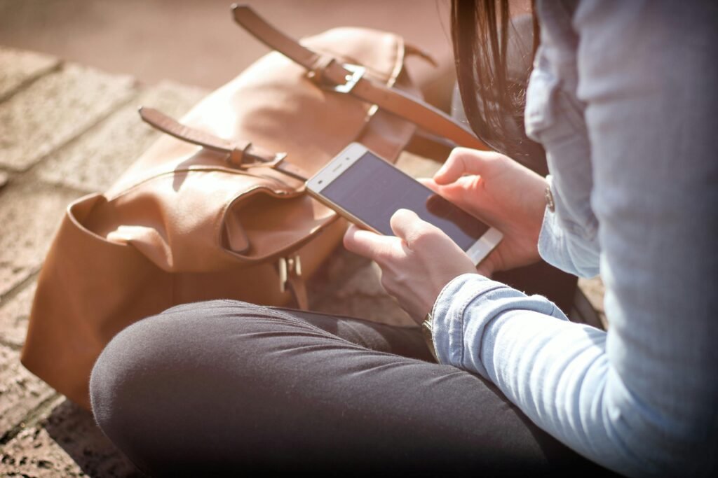 pexels-photo-359757-359757 Woman sitting with smartphone and brown bag in sunlight.